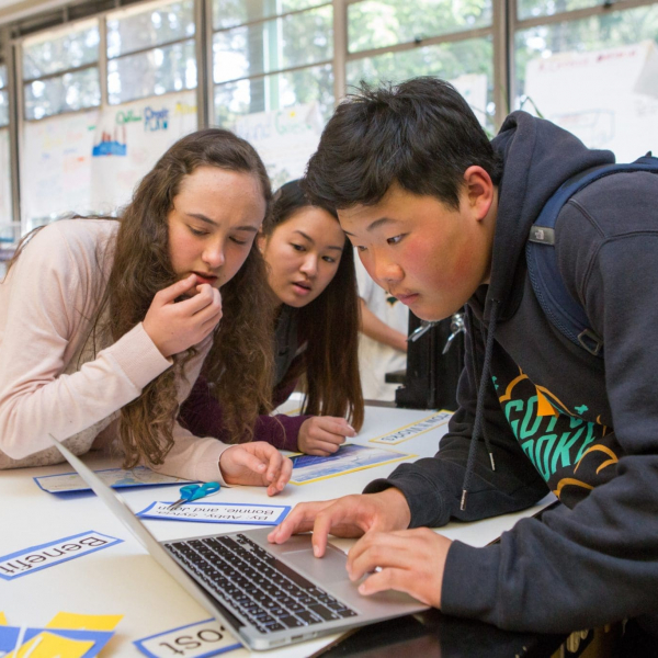 Three high school students in science class Students in a science class put the final touches on their class presentation.