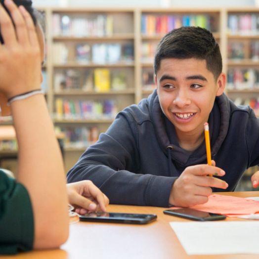 High school boy writing in library Students in deeper learning environments develop the positive mindsets necessary for academic success.